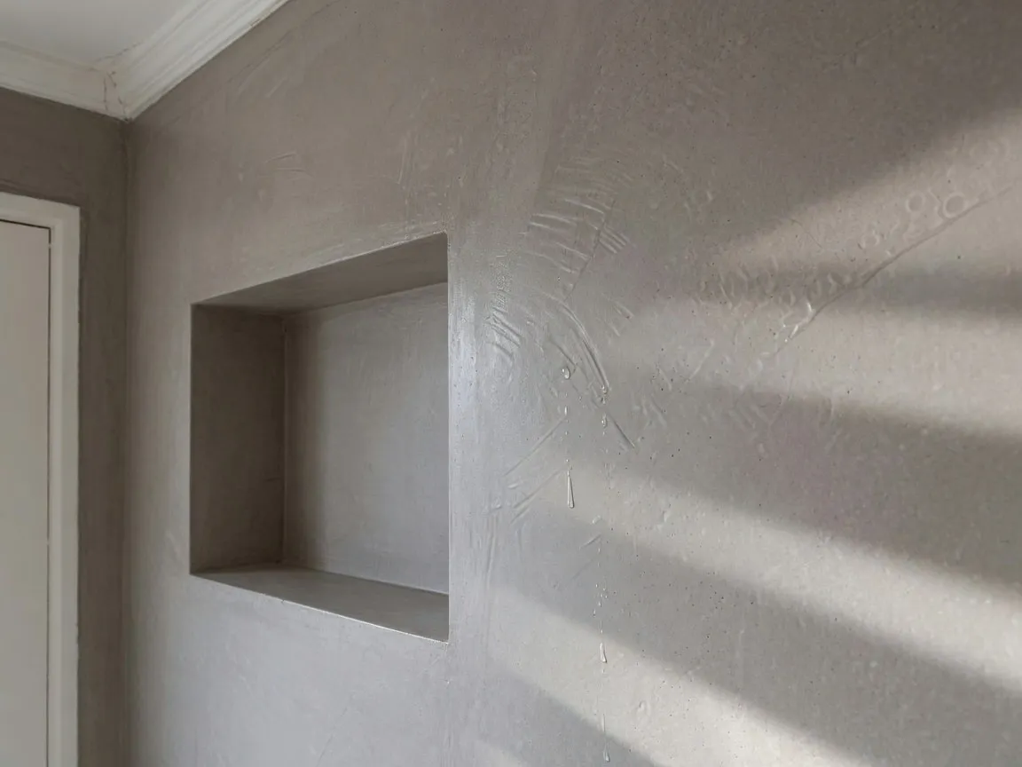 Close-up van de naadloze minerale structuur van microcement in een douchenis