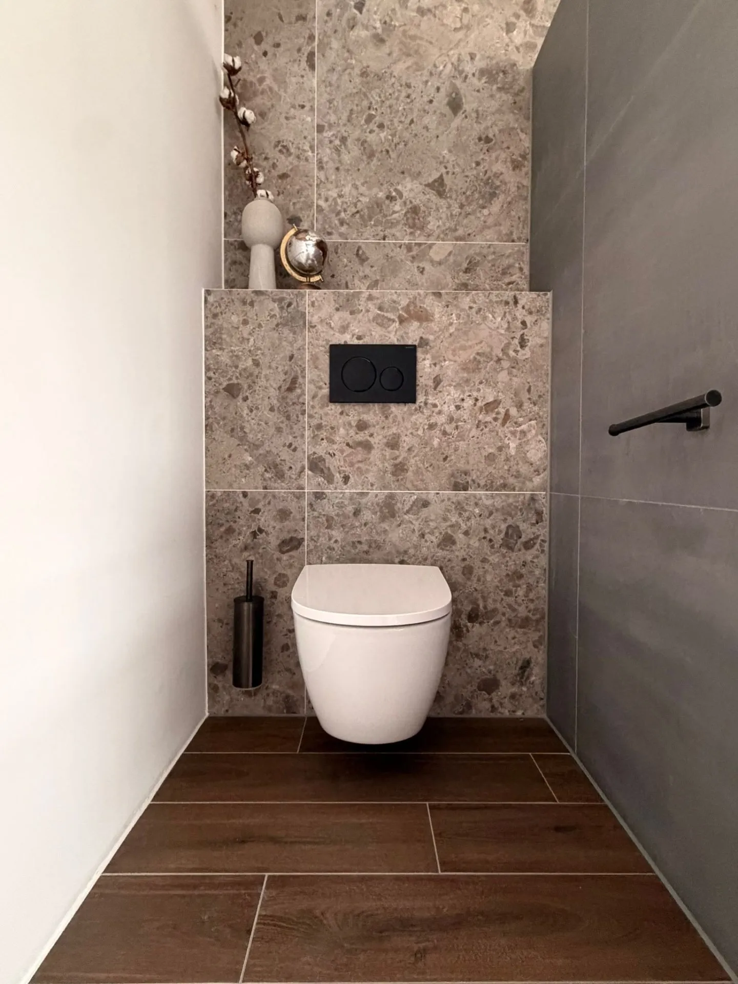 Toilet met terrazzo wand en houten vloer
